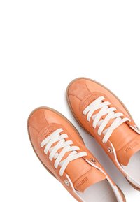 Zapatillas de cuero naranja con cordones blancos, forma redondeada y suelas de goma beige. Presentan detalles suaves de ante y una marca en relieve.