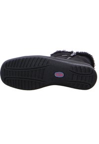 Suela de bota negra con superficie de goma texturizada, que presenta un patrón de relieve para el agarre, y un logotipo circular en azul y rojo en el centro.