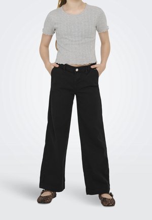 Harmaa röyhelöreunainen ribbineule crop-toppii, yhdistetty korkeat vyötäröiset mustat, leveälahkeiset housut. Jalkineissa on leopardikuosi.