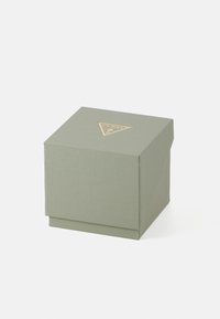 Caja de regalo verde cuadrada con una superficie texturizada y un logo dorado en forma de triángulo en la parte superior. Tapa cerrada, diseño minimalista, material de tela de algodón.
