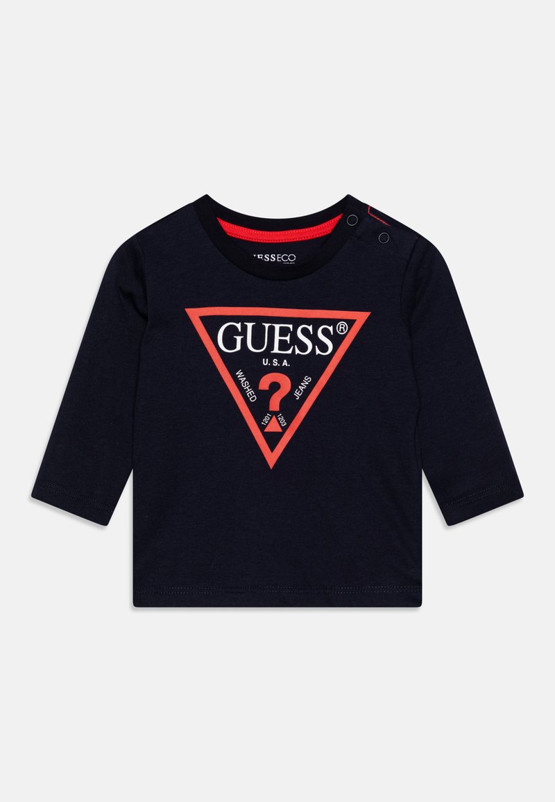 Navy long-sleeve T-shirt with red triangular logo featuring "GUESS® U.S.A." text, shoulder snaps, and a soft cotton texture.