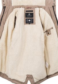 Tan outer coat with a cream, fluffy fleece lining. Features a tag with brand information and a button closure on the inner side.