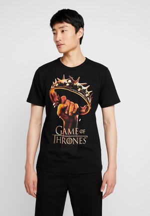 Black cotton t-shirt featuring a graphic of a hand gripping a spiked crown. "Game of Thrones" text in gold below the design.