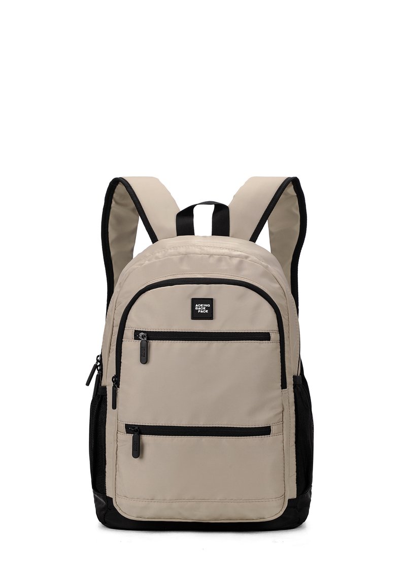 Zaino beige con accenti neri, dotato di spallacci imbottiti, molteplici tasche con zip e un piccolo logo sul davanti.