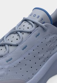 Ανοιχτό μπλε αθλητικό παπούτσι από υλικό με υφή, με διάτρητα σημεία, επίπεδα κορδόνια και αντίθετη μπλε λεπτομέρεια στο γιακά. Λογότυπο στο πλάι.