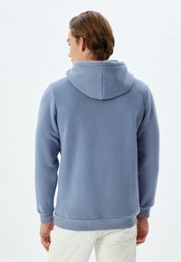 Sudadera con capucha de color azul claro, con una textura suave, puños y dobladillo acanalados. Cuenta con una capucha redonda y desenfadada para mayor comodidad.