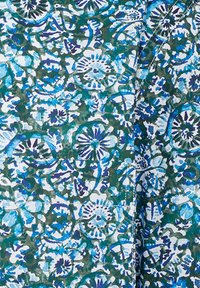 Stoff mit blumigem Muster in Blau, Teal und Weiß, der filigrane Muster von Blumen und Blättern aufweist und eine strukturierte Optik erzeugt.