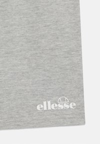 Lysegrå t-skjorte laget av myk stoff, med rund hals og en hvit "ellesse" logo nederst til høyre.