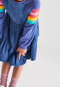 Abito in denim con maniche lunghe viola e strisce arcobaleno. Il vestito presenta un design a strati e una gonna arricciata. Tessuto confortevole.