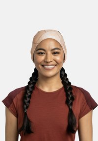 Cinta para la cabeza ligera con patrón en tonos durazno y textura suave; utilizada con una camiseta deportiva de manga corta en color óxido.