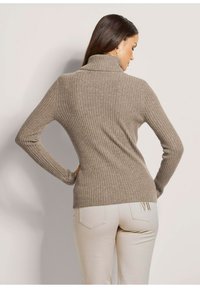 Beige gerippter Rollkragenpullover mit langen Ärmeln, der ein tailliertes Design und ein strukturiertes Material zeigt. Glatte Oberfläche mit einem dezenten, gemütlichen Aussehen.