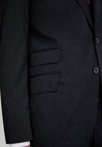 Mørkegrå jakkesætjakke med skræddersyet pasform, notch-lapel og to klaplommer, lavet af et struktureret stof med subtil glans.