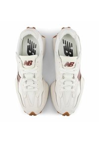 Pair of white and beige New Balance sneakers with brown logo and laces, viewed from above on a white background.