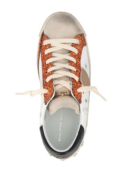 Sneaker bianca con dettagli in glitter arancioni, sezioni in suede beige, lacci crema e un tallone nero. Presenta un branding minimale sulla soletta.