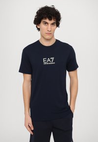 Mornarska kratka majica iz bombaža s krojem na vrat. Ima bel logo EA7 Emporio Armani na prsih. Gladka tekstura.