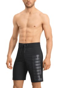 Schwarze Badehose aus schnelltrocknendem Material mit einem Kordelzugbund und großem, geprägtem "PUMA"-Logo am linken Oberschenkel.