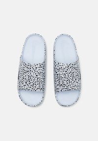 Chinelas deslizantes com padrão preto e branco, feitas de borracha, apresentando uma palmilha texturizada em azul claro e um design aberto na ponta.