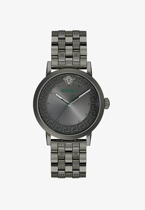 Versace sat siva s okruglim sivim brojčanikom, ukrašenim bezelom, srebrnom mrežastom narukvicom i zelenim logom. Ima dva metalna kazaljka i oznaku datuma.