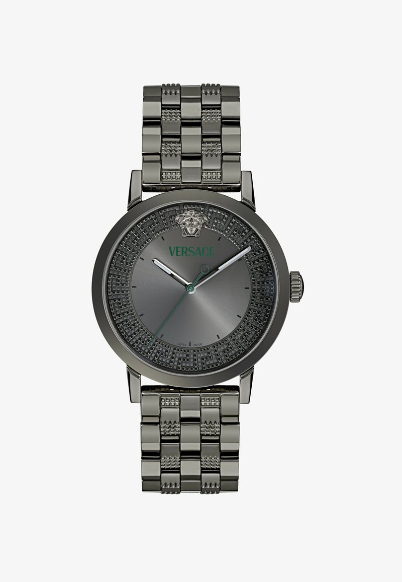 Versace laikrodis su pilku apvaliu ciferblatu, puošniu rėmeliu, sidabriniu vieliniu dirželiu ir žaliau logotipu. Jame yra dvi metalinės rodyklės ir datos žymeklis.