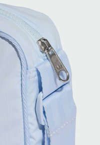 Hellblauer Stoffbeutel mit Reißverschluss. Verfügt über eine strukturierte Oberfläche, einen silbernen Reißverschlussanhänger und einen breiten Stoffriemen.