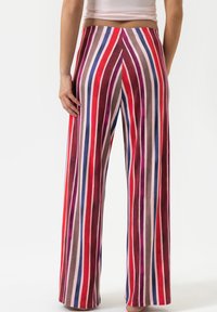 Pantalons larges à rayures verticales en rouge, rose, marron et bleu. Confectionnés dans un tissu doux et léger avec une taille élastique.