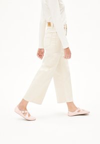 Lichtgekleurde wijde jeans gecombineerd met roze, gepatenteerde leren flats met een uitsnijding en een gesp-accent. Simpele lange mouwen top.