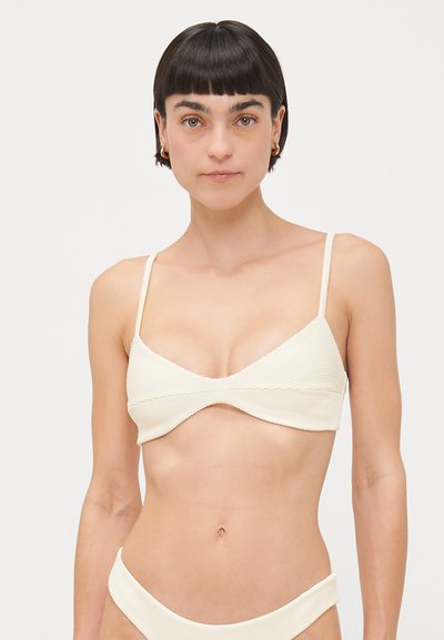 Cremfarbener, gerippter Bikini-Oberteil mit verstellbaren Trägern, einem V-Ausschnitt und gewellten Kanten. Kombiniert mit einem passenden gerippten Unterteil.