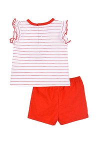 Top de rayas rojas y blancas con mangas rizadas y cierre de botón en la parte de atrás, combinado con pantalones cortos rojos sólidos, ambos hechos de una tela suave.