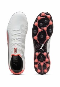 Botas de fútbol blancas con un diseño texturizado, que presentan acentos en rosa, suela negra y tacos circulares para tracción. Incluyen cordones y marca.