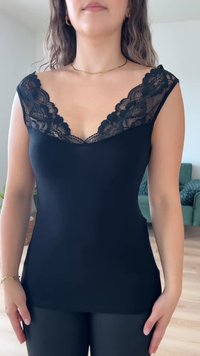 Svart tank topp med V-hals og blondekant på skuldrene. Glatt stoff med en tettsittende design som fremhever en strømlinjeformet silhuett.