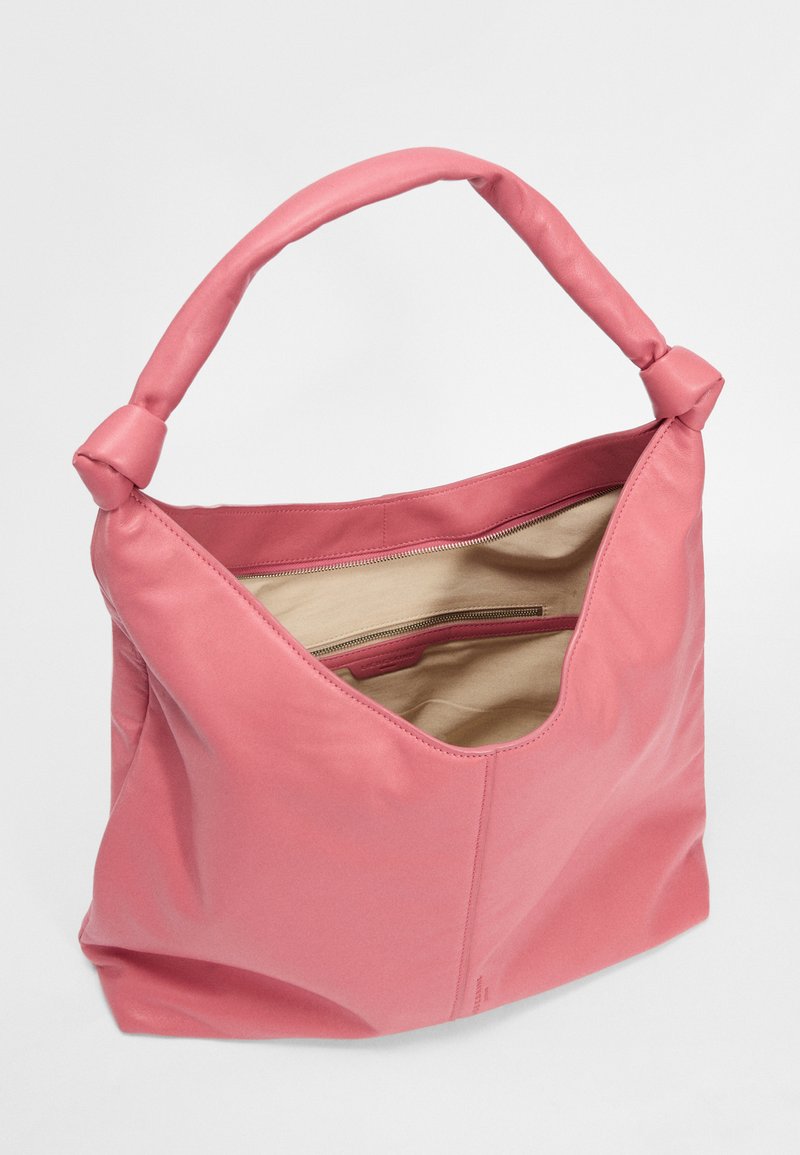 Rosa Leder-Schultertasche mit glatter Textur, Knotenstil-Griff und offenem Oberteil, das ein beiges Innenfutter mit einer Reißverschlusstasche offenbart.