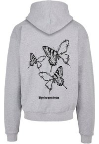 Felpa grigia con stampato un motivo di farfalla nera sulla schiena e la scritta "Dove la paura incontra la libertà" sotto il design. Realizzata in morbido cotone.