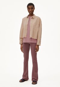 Light beige denim shirt, mauve top, and dark mauve flared pants. Smooth fabric with a pocket on the shirt, worn with dark sandals.