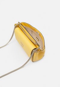 Borsa a mano in pelle gialla con tracolla a catena, texture liscia e forma strutturata. Interno con tasca con cerniera e dettagli con logo.