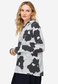 Hoodie in het wit en zwart met een bloemenpatroon, gestructureerde stof en ribbelmanchetten. "Coast Dreams" gedrukt op de voorkant.
