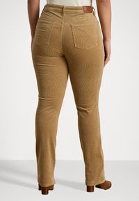 Könnyűbarna kordnadrág, hátsó zsebekkel, magas derékkal és sima felülettel. Bőr díszítés a deréknál.