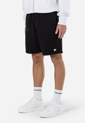 Sorte shorts lavet af bomuldsblanding med sidelommer og et lille logopatch. Kombineret med hvide sneakers og stribede sokker.