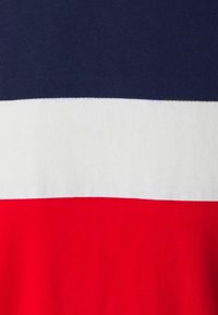 Bavlněné tričko s horizontálními pruhy: tmavě modrý nahoře, bílý uprostřed a jasně červený dole. Hladká textura.