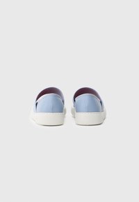 Zapatos de cuero azul tipo slip-on con suela de goma blanca, que presentan un diseño minimalista y un forro interior suave.