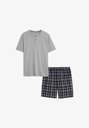 Maglietta henley corta grigia con tre bottoni, abbinata a pantaloni corti a quadri blu navy con accenti azzurri, marroni e bianchi.