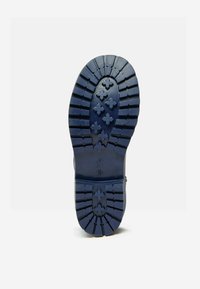 Námorná gumová podrážka so zreteľným vzorom behúňa, ktorá obsahuje krížové drážky a výstupky pre lepšiu trakciu a odolnosť.