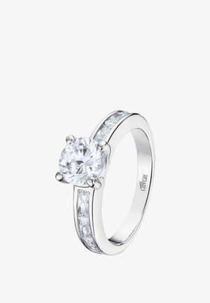 Bague en argent avec un grand gemstone rond transparent, flanqué de petites pierres rectangulaires de chaque côté, surface polie et lisse.