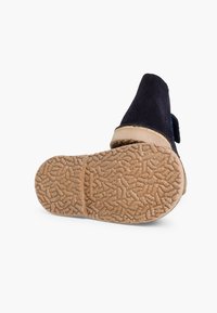 Chaussure en suede bleu foncé avec une semelle en caoutchouc beige. La semelle présente un motif texturé pour une meilleure adhérence. Le design inclut un bout arrondi et une hauteur jusqu'à la cheville.