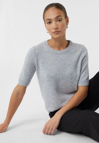 Lichtgrijze korte mouw sweater met een ronde hals en ribgebreide manchetten, gemaakt van een zachte, gestructureerde stof. Gekocht met donkere broeken.