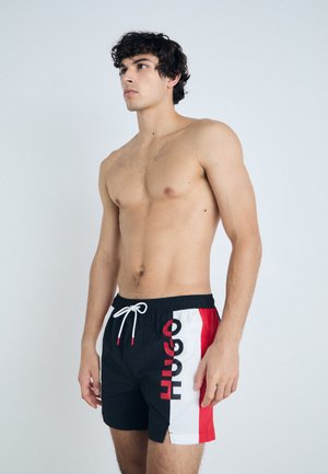 Pantaloni scurți de înot negri cu panouri laterale albe și roșii, având un logo "HUGO" proeminent. Materialul este ușor, cu o talie elastică.