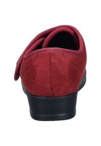 Red suede slip-on shoe with a rounded toe, featuring a black textured sole and elastic gussets for easy wear. Smooth fabric and simple design.