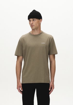 Olive green cotton t-shirt with short sleeves, crew neck, and small "GABBA" logo; paired with black pants and a black ribbed beanie.