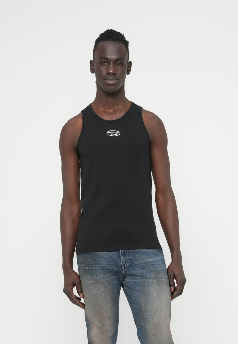 Μαύρο αμάνικο τοπ από βαμβάκι, με στρογγυλή λαιμόκοψη και μικρό λευκό λογότυπο στο στήθος. Συνδυάζεται με ξεθωριασμένο μπλε τζιν.