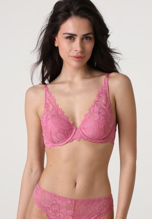 Reggiseno rosa in pizzo con motivi floreali, scollatura profonda e spalline regolabili, abbinato a culotte in pizzo coordinate. Tessuto morbido e testurizzato.