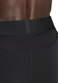 Schwarze Sportshorts mit einem breiten elastischen Bund, glatter Textur und flachen Nähten für mehr Komfort. Die Details der Nähte sind sichtbar.